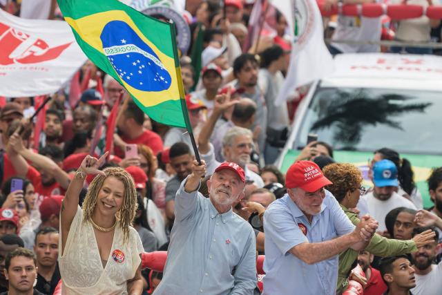 Brazil's President and presidential candidate Luiz Inacio Lula da Silva (C) waves a national flag next to former federal deputy Aurea Carolina (L) and federal deputy Patrus Ananias (R) during a campaign rally in Belo Horizonte, Minas Gerais state, Brazil on October 2, 2026. Brazilians go to the polls on October 4, 2026, in a tight race led by leftist President Luiz Inacio Lula da Silva and right-wing senator Flavio Bolsonaro, son of former president Jair Bolsonaro. (Photo by Gledston TAVARES / AFP)