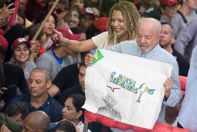 Brazil's President and presidential candidate Luiz Inacio Lula da Silva (R) shows a sign reading in Portuguese "Brazil is for Brazilians" with former federal deputy Aurea Carolina (L) during a campaign rally in Belo Horizonte, Minas Gerais state, Brazil on October 2, 2026. Brazilians go to the polls on October 4, 2026, in a tight race led by leftist President Luiz Inacio Lula da Silva and right-wing senator Flavio Bolsonaro, son of former president Jair Bolsonaro. (Photo by Gledston Tavares / AFP)