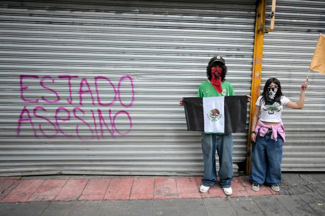 A demonstrator holds a Mexican flag in black and white during a demonstration marking the 58th anniversary of the 1968 Tlatelolco student massacre in Mexico City on October 2, 2026. (Photo by Alfredo ESTRELLA / AFP)