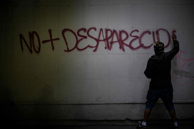 A demonstrator makes a graffiti during a demonstration marking the 58th anniversary of the 1968 Tlatelolco student massacre in Mexico City on October 2, 2026. (Photo by Alfredo ESTRELLA / AFP)