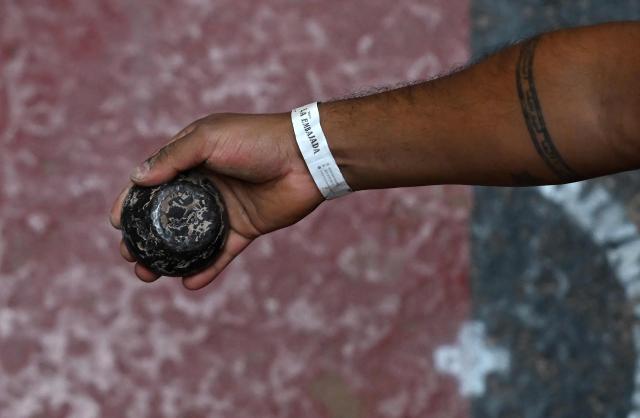 A member of the Swiss delegation holds a tejo during the fourth edition of the Tejo World Championship, a traditional Colombian sport, in Bogota on October 2, 2026. Tejo is Colombia's national sport, in which players throw a heavy metal disc at a clay-filled target, aiming to hit small gunpowder-filled packets that explode on impact. (Photo by Raul ARBOLEDA / AFP)