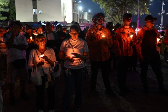People hold candles during a vigil and prayer service called "Beam of Light," marking 100 days since the twin earthquakes that struck Venezuela on June 24, killing and displacing thousands of people, in Caraballeda, La Guaira state, Venezuela, on October 2, 2026. (Photo by Juan BARRETO / AFP)