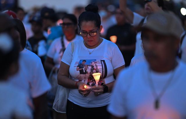 A woman holds candles during a vigil and prayer service called "Beam of Light," marking 100 days since the twin earthquakes that struck Venezuela on June 24, killing and displacing thousands of people, in Caraballeda, La Guaira state, Venezuela, on October 2, 2026. (Photo by Juan BARRETO / AFP)