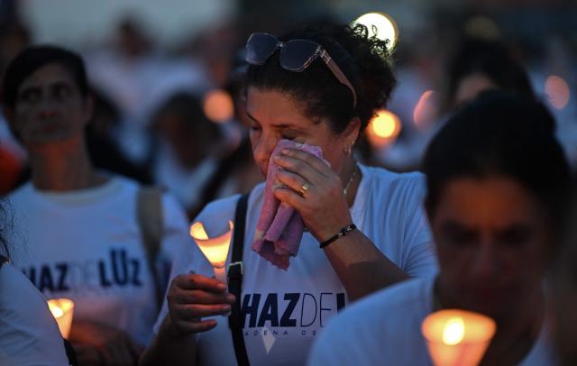 A woman wipes away tears while holding a candle during a vigil and prayer service called "Beam of Light," marking 100 days since the twin earthquakes that struck Venezuela on June 24, killing and displacing thousands of people, in Caraballeda, La Guaira state, Venezuela, on October 2, 2026. (Photo by Juan BARRETO / AFP)