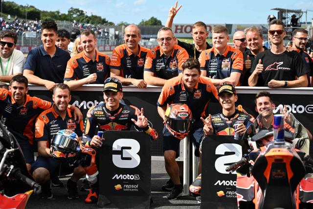 Second placed Red Bull KTM Ajo rider Brian Uriarte of Spain (R) and third placed Red Bull KTM Ajo rider Alvaro Carpe of Spain (L) pose with their team officers at the Parc Ferme of the Moto3 class qualifying session of MotoGP Japanese Grand Prix at the Mobility Resort Motegi in Motegi, Tochigi prefecture on October 3, 2026. (Photo by Toshifumi KITAMURA / AFP)
