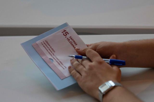 A member of the electoral commission prepares a ballot paper before handing it to a voter in a polling station in Riga during the general elections in Latvia on October 3, 2026. (Photo by Wojtek RADWANSKI / AFP)