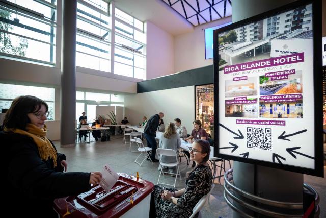 A voter casts the voting ballot into the ballot box at a polling station located in a shopping centre in Riga during the general elections in Latvia on on October 3, 2026. (Photo by Wojtek RADWANSKI / AFP)