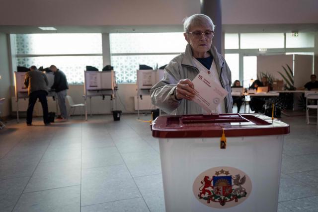 A voter casts the voting ballot into the ballot box at a polling station in Riga during the general elections in Latvia on October 3, 2026. (Photo by Wojtek RADWANSKI / AFP)