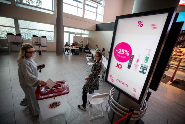 A voter casts the voting ballot into the ballot box at a polling station located in a shopping centre in Riga during the general elections in Latvia on on October 3, 2026. (Photo by Wojtek RADWANSKI / AFP)