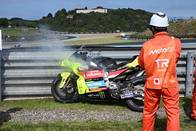 Course marshalls watch smoke rising from the motorcycle of ITALJET Gresini Moto2 rider Alonso Lopez of Spain during the Tissot Sprint race of MotoGP Japanese Grand Prix at the Mobility Resort Motegi in Motegi, Tochigi prefecture on October 3, 2026. (Photo by Toshifumi KITAMURA / AFP)