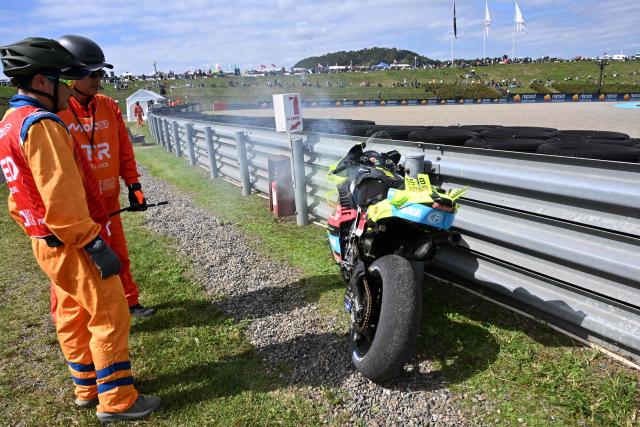 Course marshalls watch smoke rising from the motorcycle of ITALJET Gresini Moto2 rider Alonso Lopez of Spain during the Tissot Sprint race of MotoGP Japanese Grand Prix at the Mobility Resort Motegi in Motegi, Tochigi prefecture on October 3, 2026. (Photo by Toshifumi KITAMURA / AFP)