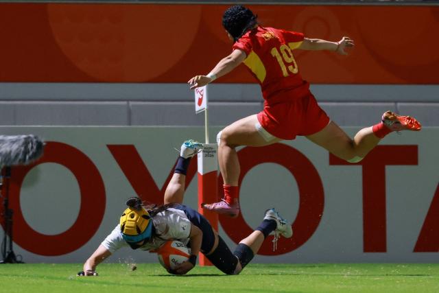 Japan's Marin Kajiki (C) scores a try as China's Chen Can jumps over her in the women's rugby sevens final match between Japan and China during the 2026 Asian Games at the Mizuho Park Rugby Field in Nagoya on October 3, 2026. (Photo by DAVID GRAY / AFP)