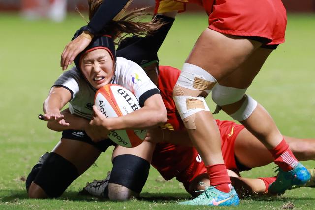 Japan's Natsuki Ouchida (L) is tackled in the women's rugby sevens final match between Japan and China during the 2026 Asian Games at the Mizuho Park Rugby Field in Nagoya on October 3, 2026. (Photo by DAVID GRAY / AFP)