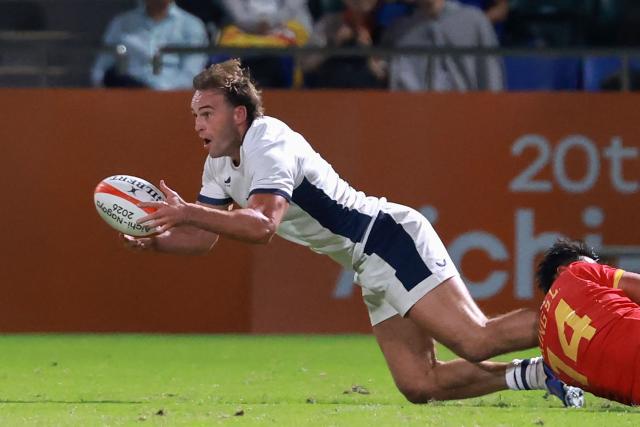 Hong Kong's Harry Sayers (L) passes the ball as he is tackled in the men's rugby sevens final match between Hong Kong and China during the 2026 Asian Games at the Mizuho Park Rugby Field in Nagoya on October 3, 2026. (Photo by DAVID GRAY / AFP)