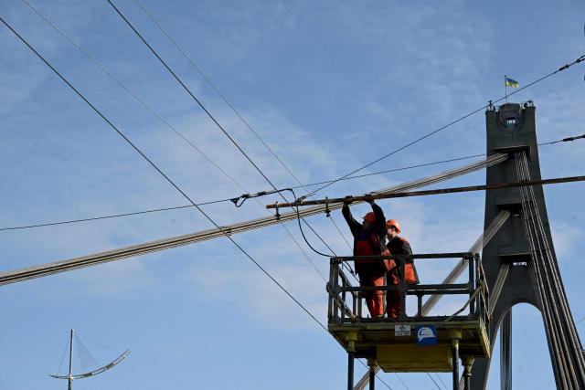 Technicians repair a trolleybus power line that was damaged following a drone attack on the Northern Bridge in Kyiv on October 3, 2026, amid Russian invasion of Ukraine. A Russian strike targeted a major bridge in Kyiv, its mayor said October 3, in another attack on Ukrainian infrastructure that has brought traffic chaos to the capital. The attack on the Northern Bridge, which followed a drone alert, came a day after the Southern Bridge was hit in a wave of strikes that city officials say is "tearing Kyiv apart". (Photo by Sergei SUPINSKY / AFP)
