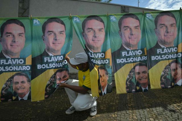 A man hangs towels for sale during Brazil's right-wing senator and presidential candidate Flavio Bolsonaro campaign rally on the eve of the general election, in Santa Barbara d'Oeste, state of Sao Paulo, Brazil on October 3, 2026. Brazilians go to the polls on October 4, 2026, in a tight race led by leftist President Luiz Inacio Lula da Silva and right-wing senator Flavio Bolsonaro, son of imprisoned former president Jair Bolsonaro. (Photo by NELSON ALMEIDA / AFP)