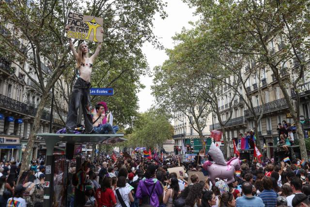 A demonstrator holds a placard reading "these fascists are pissing me off" (topL) during the 2026 LGBT+ Paris Pride march in Paris on October 3, 2026. (Photo by Kenzo TRIBOUILLARD / AFP)