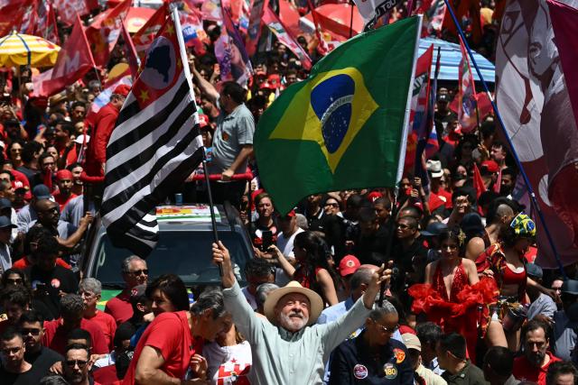 Brazil's President and presidential candidate Luiz Inacio Lula da Silva (C) waves a national flag (L) and a Sao Paulo's state flag flanked by his candidate for Sao Paulo's governor, Fernando Haddad (L) and the Minister of the Environment Marina Silva during a campaign rally on the eve of the general election, in Sao Paulo, Brazil on October 3, 2026. Brazilians go to the polls on October 4, 2026, in a tight race led by leftist President Luiz Inacio Lula da Silva and right-wing senator Flavio Bolsonaro, son of imprisoned former president Jair Bolsonaro. (Photo by Luis ROBAYO / AFP)
