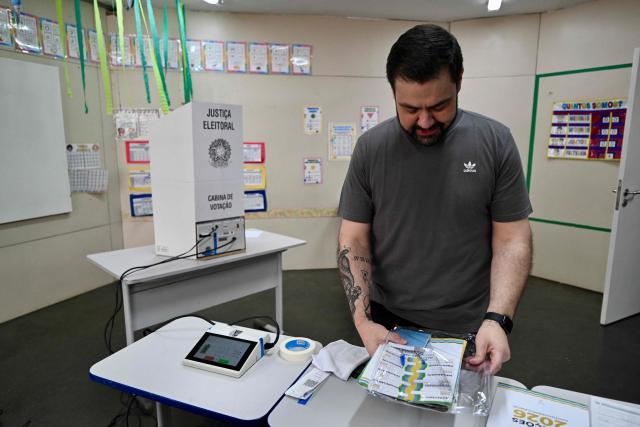 An employee of the Regional Electoral Court (TRE) sets up a voting booth at a polling station in a school in Brasília, Brazil, on October 3, 2026, on the eve of the general election. Brazilians go to the polls on October 4, 2026, in a tight race led by leftist President Luiz Inacio Lula da Silva and right-wing senator Flavio Bolsonaro, son of former president Jair Bolsonaro, who is serving house arrest. (Photo by Evaristo Sa / AFP)