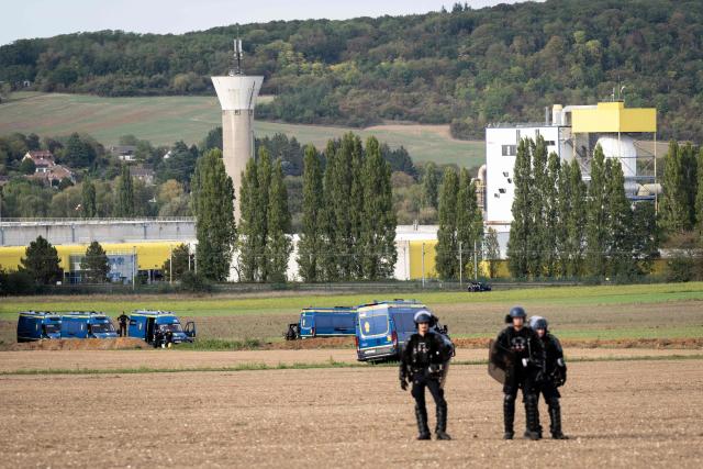 Gendarmerie officers stand in a field in front of the Syngenta factory, in the background, during a demonstration as part of an international day of mobilisation against the site, which produces pesticides, to denounce the agrochemical industry and demand its shutdown, in Saint-Pierre-la-Garenne, Normandy, on October 3, 2026. (Photo by Guillaume SALIGOT / AFP)