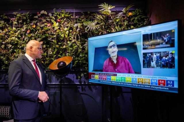 Latvia's Prime Minister Andris Kulbergs looks at a television screen after the first exit poll results of the parliamentary election were announced during an election night event of his centre-right Apvienotais Saraksts (United List) party in Riga on October 3, 2026. (Photo by Wojtek RADWANSKI / AFP)