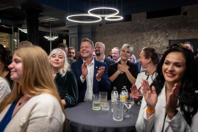 Supporters of Latvia's Prime Minister Andris Kulbergs applaud as he speaks after the first exit poll results of the parliamentary election were announced during an election night event of his centre-right Apvienotais Saraksts (United List) party in Riga on October 3, 2026. (Photo by Wojtek RADWANSKI / AFP)