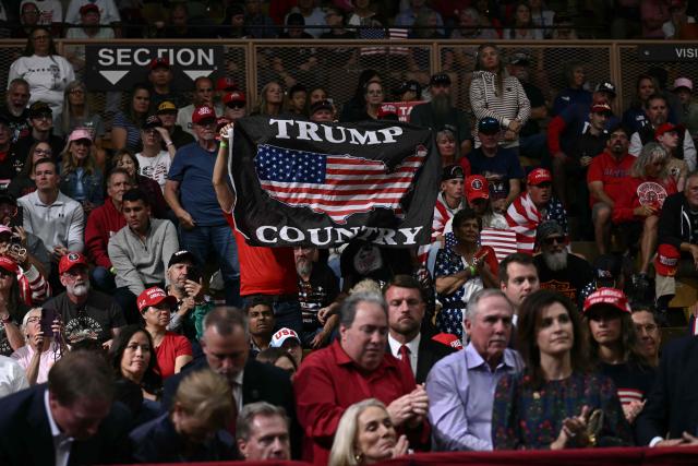 A supporter holds a "Trump Country" flag as US President Donald Trump speaks during a campaign rally in Vandalia, Ohio, on October 3, 2026. (Photo by Brendan SMIALOWSKI / AFP)