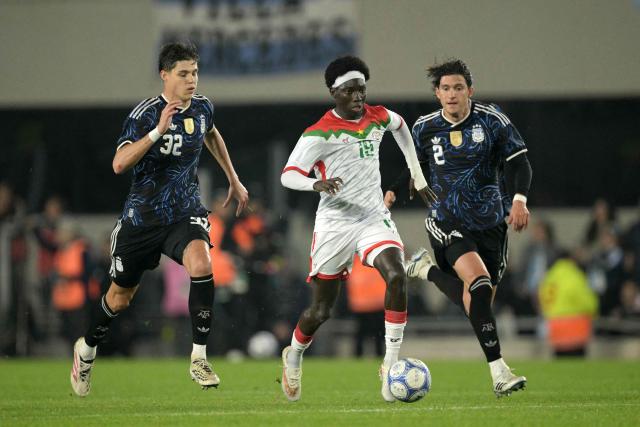 Burkina Faso's midfielder #19 Mohamed Zongo (C) runs with the ball past Argentina's defender #32 Tomas Palacios and defender #02 Leonardo Balerdi during the international friendly football match between Argentina and Burkina Faso at the Mas Monumental stadium in Buenos Aires on October 3, 2026. (Photo by JUAN MABROMATA / AFP)