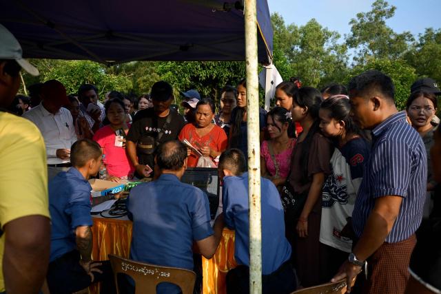 People register for entry to the Myanmar Navy base in Thanlyin on October 4, 2026, as families gather to welcome returnees arriving from Malaysia. Nearly 1,500 Myanmar migrants from Malaysia arrived in their war-torn home country on October 4, a Myanmar official said, returned under an opaque repatriation scheme that rights monitors say cannot assure their safety. (Photo by Sai Aung MAIN / AFP)