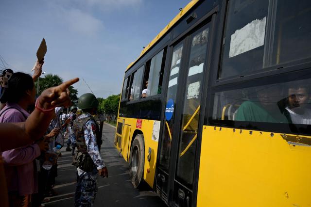 Migrants returning from Malaysia look out from a bus upon their arrival at the Myanmar Navy base in Thanlyin on October 4, 2026. Nearly 1,500 Myanmar migrants from Malaysia arrived in their war-torn home country on October 4, a Myanmar official said, returned under an opaque repatriation scheme that rights monitors say cannot assure their safety. (Photo by Sai Aung MAIN / AFP)