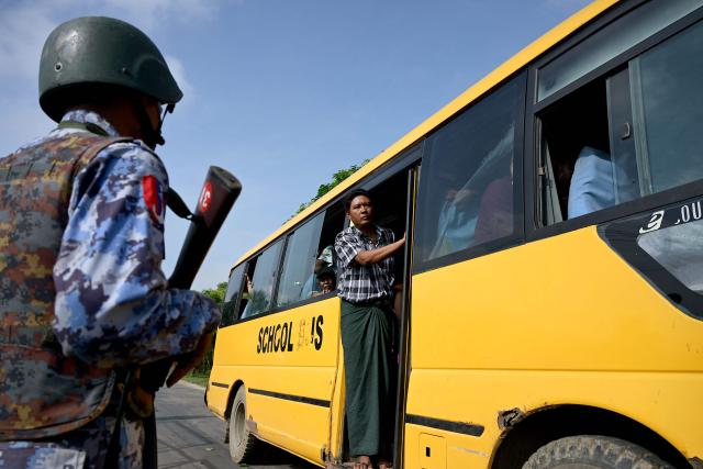 TOPSHOT - Migrants returning from Malaysia look out from a bus upon their arrival at the Myanmar Navy base in Thanlyin on October 4, 2026. Nearly 1,500 Myanmar migrants from Malaysia arrived in their war-torn home country on October 4, a Myanmar official said, returned under an opaque repatriation scheme that rights monitors say cannot assure their safety. (Photo by Sai Aung MAIN / AFP)