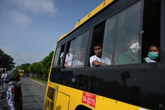 Migrants returning from Malaysia look out from a bus upon their arrival at the Myanmar Navy base in Thanlyin on October 4, 2026. Nearly 1,500 Myanmar migrants from Malaysia arrived in their war-torn home country on October 4, a Myanmar official said, returned under an opaque repatriation scheme that rights monitors say cannot assure their safety. (Photo by Sai Aung MAIN / AFP)
