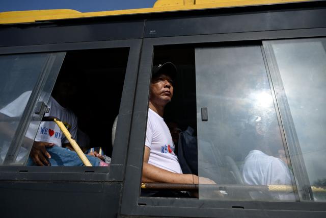 Migrants returning from Malaysia look out from a bus upon their arrival at the Myanmar Navy base in Thanlyin on October 4, 2026. Nearly 1,500 Myanmar migrants from Malaysia arrived in their war-torn home country on October 4, a Myanmar official said, returned under an opaque repatriation scheme that rights monitors say cannot assure their safety. (Photo by Sai Aung MAIN / AFP)