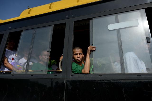 Migrants returning from Malaysia look out from a bus window upon their arrival at the Myanmar Navy base in Thanlyin on October 4, 2026. Nearly 1,500 Myanmar migrants from Malaysia arrived in their war-torn home country on October 4, a Myanmar official said, returned under an opaque repatriation scheme that rights monitors say cannot assure their safety. (Photo by Sai Aung MAIN / AFP)