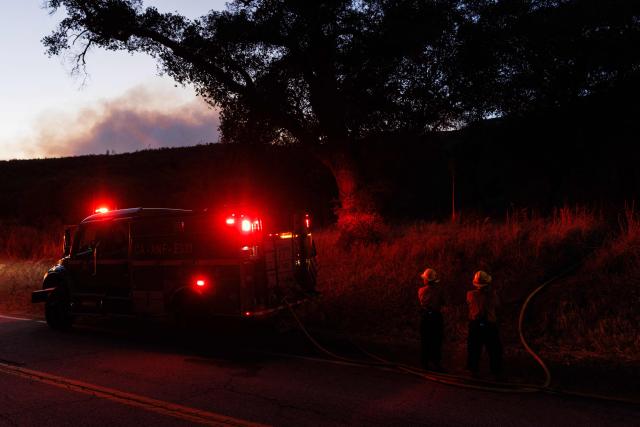A US Department of Agriculture Forest Service fire crew runs a hose for water to battle the Bouquet Fire as it burns in the Angeles National Forest near Santa Clarita, California on October 3, 2026. The fire, which has prompted evacuation orders in the area, come as an extended heat wave hits Southern California. (Photo by Blake Fagan / AFP)