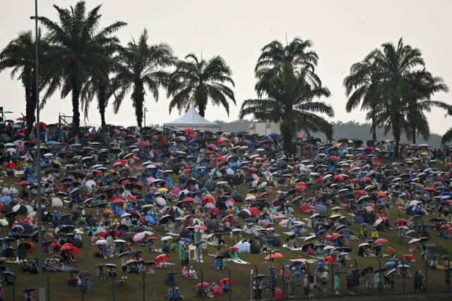 Spectators hold umbrellas as the rain delayed the start of the Formula One Bahrain Grand Prix in Sepang on October 4, 2026. (Photo by Jade Gao / AFP)