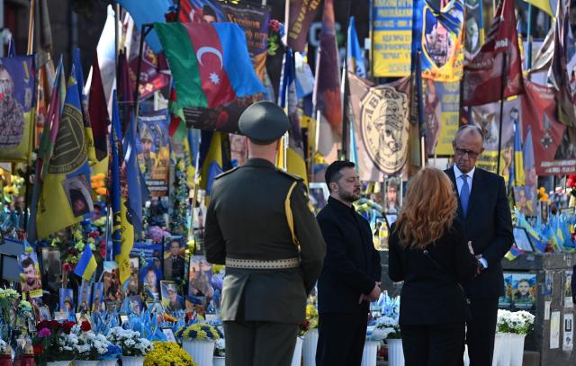 Ukraine's President Volodymyr Zelensky (2ndL) and Germany's Chancellor Friedrich Merz (R) stand next to a makeshift memorial for Ukrainian and foreign soldiers on Independence Square in Kyiv on October 4, 2026, amid the Russian invasion of Ukraine. (Photo by Sergei SUPINSKY / AFP)