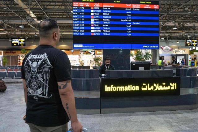 A passenger looks at a flight information display at Al-Najaf Al-Ashraf International Airport in the central holy city of Najaf on October 4, 2026. The United States has granted sanctions exemptions for some Iranian airlines to operate flights to Iraq's holy city of Najaf, the Iraqi prime minister's office said on October 2, as Washington targets Iran's aviation sector to choke its economy in the Middle East war. (Photo by Qassem al-KAABI / AFP)