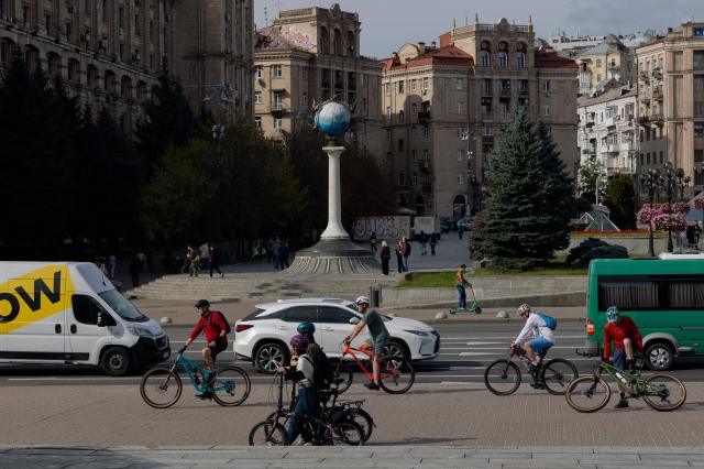 Cyclists ride on Independence Square in Kyiv on October 4, 2026, amid the Russian invasion of Ukraine. (Photo by Tetiana DZHAFAROVA / AFP)