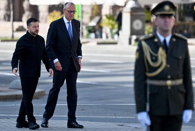 Ukraine's President Volodymyr Zelensky (L) and Germany's Chancellor Friedrich Merz meet prior to a ceremony near a makeshift memorial for Ukrainian and foreign soldiers on Independence Square in Kyiv on October 4, 2026, amid the Russian invasion of Ukraine. (Photo by Sergei SUPINSKY / AFP)