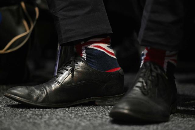 Britain's main opposition Conservative Party Shadow Home Secretary Chris Philp shows off his Union flag socks in the main hall on the first day of the annual Conservative Party conference in Birmingham, central England, on October 4, 2026.  (Photo by Oli SCARFF / AFP)