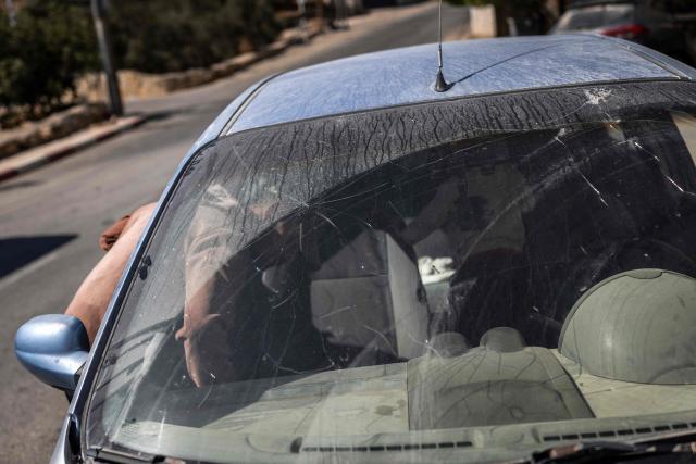 A man inspects a damaged car parked along the road in al-Mughayyir village near Ramallah in the Israeli-occupied West Bank, on October 4, 2026. (Photo by Ilia YEFIMOVICH / AFP)