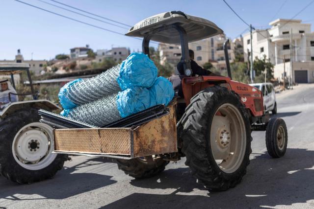 A worker transports fence material on a tractor along the road in al-Mughayyir village near Ramallah in the Israeli-occupied West Bank, on October 4, 2026. (Photo by Ilia YEFIMOVICH / AFP)