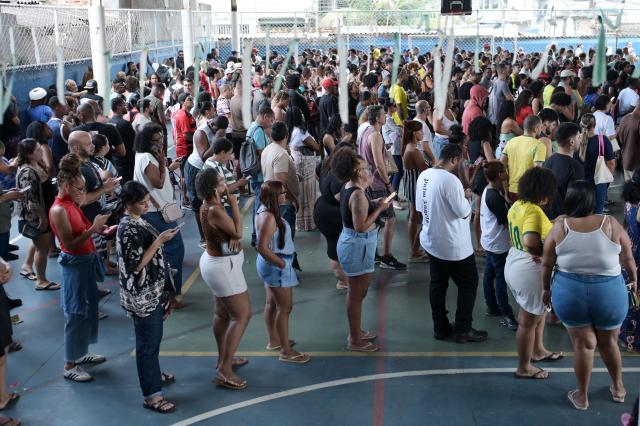 People queue at a polling station in Rio de Janeiro, Brazil, on October 4, 2026, during the presidential election. Brazilians head to the polls in a highly polarized presidential election between incumbent leftist President Luiz Inacio Lula da Silva -seeking a fourth presidential mandate- and right-wing senator Flavio Bolsonaro, who emerged as the leading figure of the conservative movement following the conviction and imprisonment of his father, former president Jair Bolsonaro. (Photo by TERCIO TEIXEIRA / AFP)