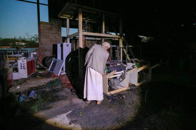 A Yemeni man inspects damaged machinery inside a foam factory after a strike that Houthi authorities-run media attributed to Saudi Arabia, in the Shamlan neighbourhood of Yemen's capital Sanaa on October 4, 2026. Yemen relapsed into war in July after years of calm, drawn into the regional conflict triggered by the US-Israeli offensive against Iran that began at the end of February. (Photo by Mohammed HUWAIS / AFP) / 