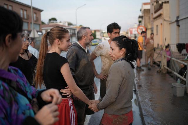 Resident Rebeca Langa (R) is comforted by a neighbour next to her flooded house after torrential rains in Pineda de Mar, north of Barcelona, on October 4, 2026. Torrential rains battering eastern Spain have left two dead and kept the city of Barcelona and its surrounding areas on high alert, authorities said today, warning of the risk of flooding and overflowing rivers. (Photo by Manaure QUINTERO / AFP)