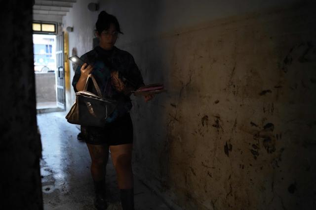 A woman walks along a wall where the water level is seen after floods due to torrential rains in Pineda de Mar, north of Barcelona, on October 4, 2026. Torrential rains battering eastern Spain have left two dead and kept the city of Barcelona and its surrounding areas on high alert, authorities said today, warning of the risk of flooding and overflowing rivers. (Photo by Manaure QUINTERO / AFP)