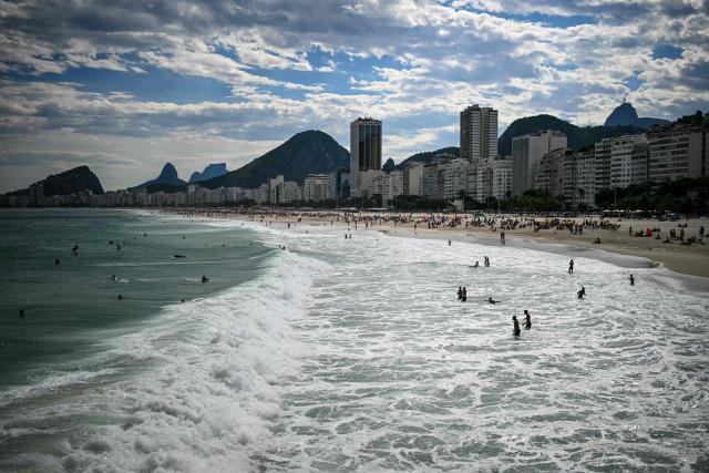 People enjoy Copacabana Beach in Rio de Janeiro, Brazil, on October 4, 2026, during the presidential election. Brazilians head to the polls in a highly polarized presidential election between incumbent leftist President Luiz Inacio Lula da Silva -seeking a fourth presidential mandate- and right-wing senator Flavio Bolsonaro, who emerged as the leading figure of the conservative movement following the conviction and imprisonment of his father, former president Jair Bolsonaro. (Photo by MAURO PIMENTEL / AFP)