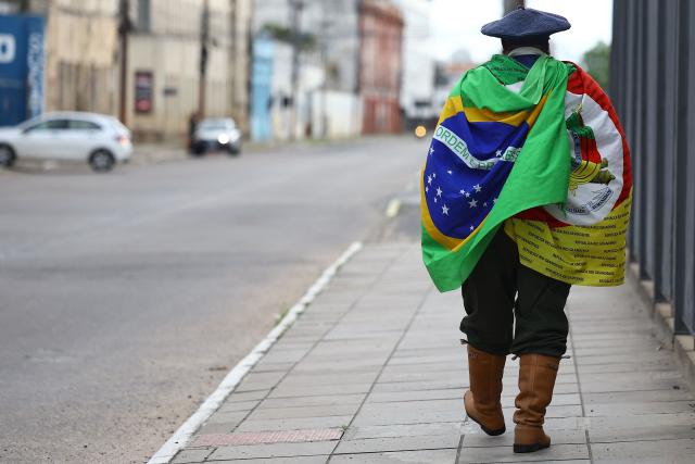 A supporter of Brazil's right-wing senator and presidential candidate Flavio Bolsonaro of the Liberal Party (PL) walks along a street after polls closed in the general election in Porto Alegre, Brazil, on October 4, 2026. Brazilians waited anxiously for the results of a tight election race between President Luiz Inacio Lula and Flavio Bolsonaro that will determine if the Latin American powerhouse joins a regional swing to the right championed by US President Donald Trump. (Photo by SILVIO AVILA / AFP)