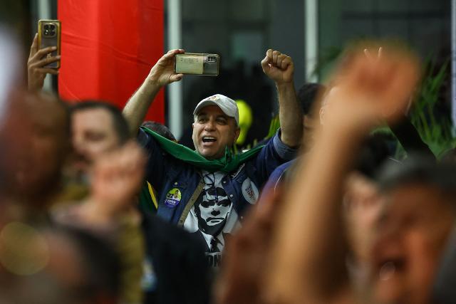 A supporter of Brazil's right-wing presidential candidate Flavio Bolsonaro reacts after the first results of the presidential election in in Porto Alegre, Brazil, on October 4, 2026. Brazilians waited anxiously on October 4, 2026, for the results of a tight election race between President Luiz Inacio Lula da Silva and Flavio Bolsonaro that will determine if the Latin American powerhouse joins a regional swing to the right championed by US President Donald Trump. (Photo by SILVIO AVILA / AFP)